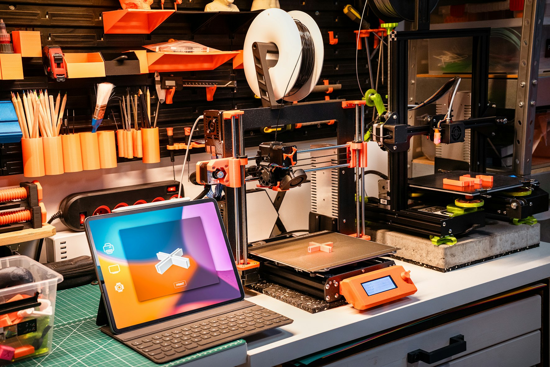 Laptop displaying 3D model next to a 3D printer
